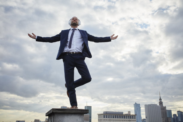伸开双臂迎着风。商人在屋顶上保持平衡图片下载