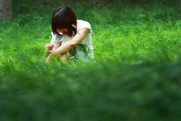 悲伤的女孩坐在草地上图片下载