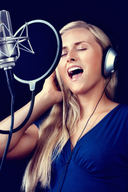 年轻女子戴着耳机，用麦克风唱歌图片下载