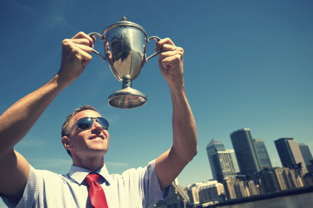 胜利的商人把奖杯举向天际线图片下载