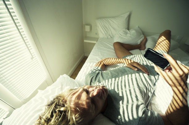 男人在床上用智能手机放松图片下载