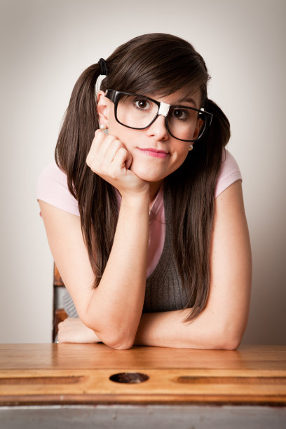 无聊，书呆子年轻女学生坐在课桌上图片下载