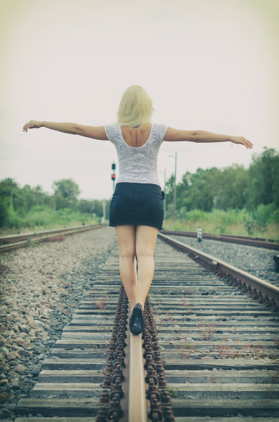 漂亮的金发女人在铁路上摆姿势。图片下载