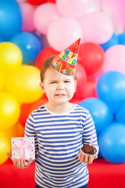 愤怒的3岁女孩拿着生日蛋糕和礼物图片下载