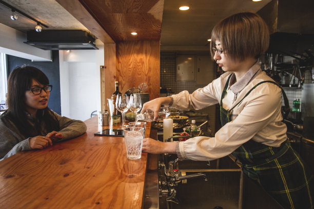 年轻的女服务员在厨房柜台上为顾客倒水图片下载