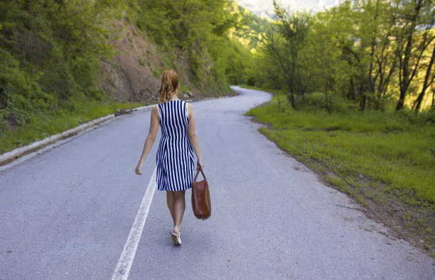 女旅行家提着行李箱在路上行走图片下载