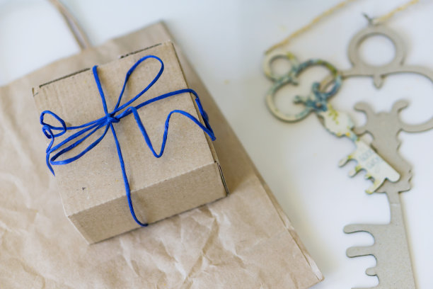 一个礼品盒的特写与一个礼品袋由牛皮纸在白色的桌子上。聚焦深度浅。爱的概念。图片下载
