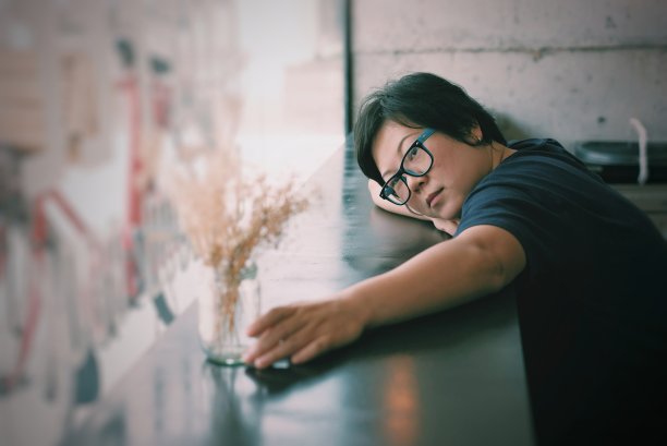 亚洲女性40多岁，白皙的皮肤，穿着黑色的衣服，戴着眼镜，有一个怀疑和思考的姿态，在咖啡馆咖啡馆图片下载