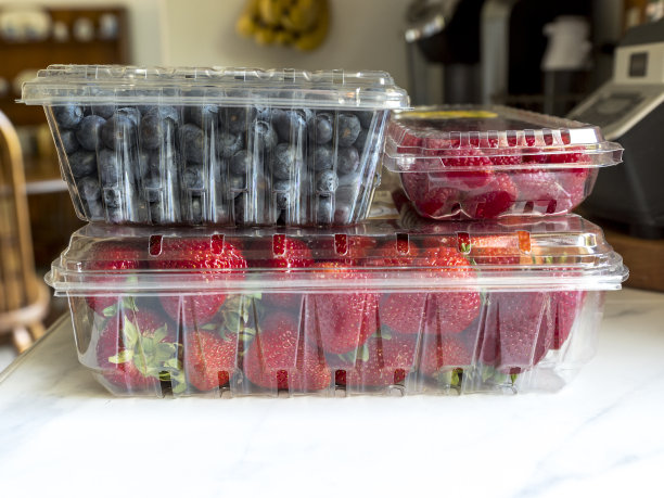 覆盆子，蓝莓，草莓，新鲜塑料容器厨房柜台图片下载