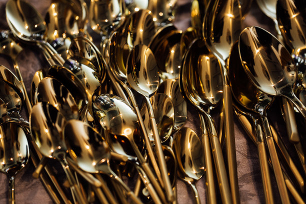 闪亮的勺子的特写，随机混乱地躺在桌子上。温暖的黄色晚会灯光图片下载
