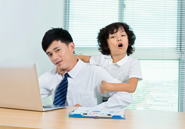 小男孩站在他工作的父亲后面图片下载