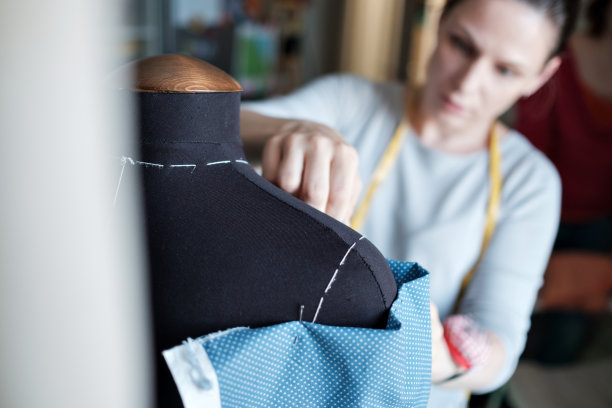 年轻的白人女性时装设计师测量一件衣服。图片下载