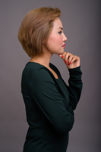 工作室拍摄的美丽的亚洲女人短发穿着长袖绿色连衣裙，以灰色的背景图片下载