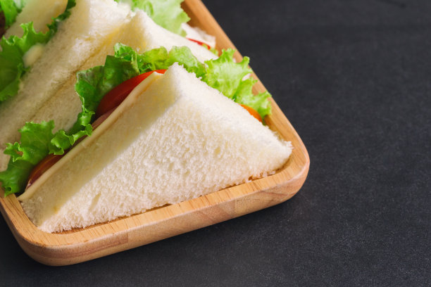 夹有生菜和番茄的三明治火腿芝士片。自制的三明治配橙汁作为早餐或午餐。美味的火腿芝士三明治准备上桌了。图片下载