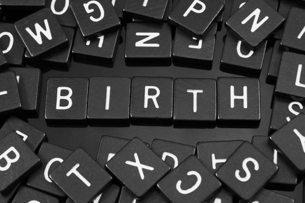 黑色字母瓷砖拼出单词“birth”素材图片