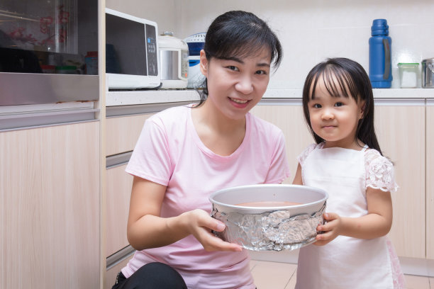 亚裔华人妈妈和女儿一起烤蛋糕图片下载
