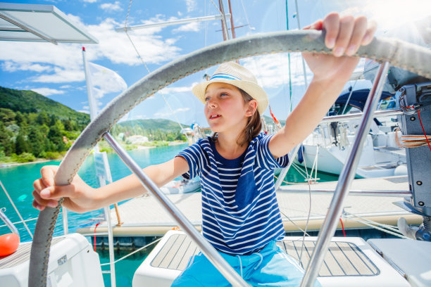一个小男孩在夏季巡航的帆船上当船长。旅行冒险，与孩子的家庭度假游艇图片下载