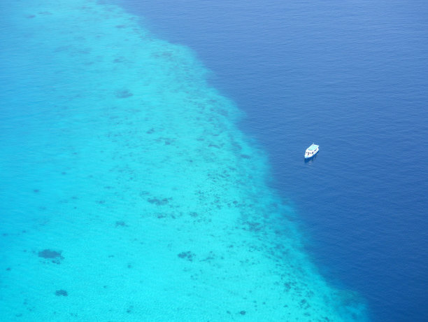 鸟瞰图，旅游渡轮漂浮在马尔代夫环礁附近，著名的热带印度洋目的地在亚洲。马尔代夫以广阔的珊瑚礁、海滩和蓝色泻湖而闻名。图片下载