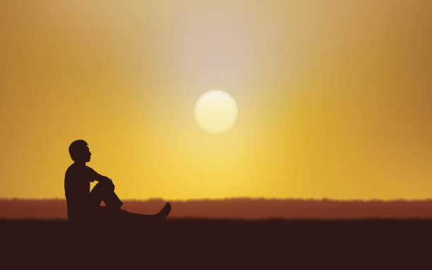 在日落天空的背景下，一个人坐在地上的剪影图片下载