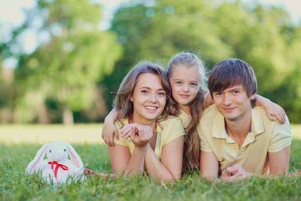 幸福的一家人躺在公园的草地上图片下载
