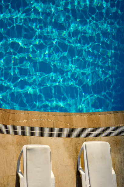 在晴天拍摄的游泳池和日光浴床图片下载