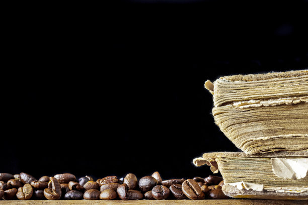 咖啡豆和旧书放在木桌上，黑色空白背景，留出文字空间。模型图片下载