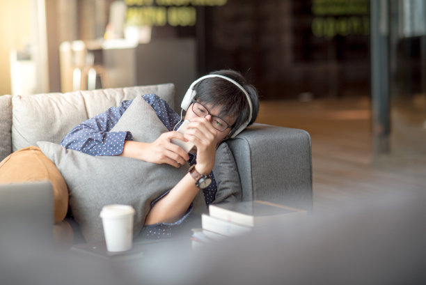 年轻的亚洲男子在沙发上使用智能手机图片下载