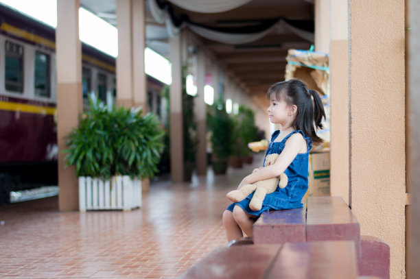 可爱的亚洲女童坐在棕色泰迪熊木沙发上（选择性焦点）图片下载