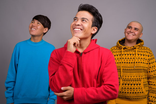 一群身穿保暖服装的亚洲年轻男士的影棚照片，灰色背景图片下载