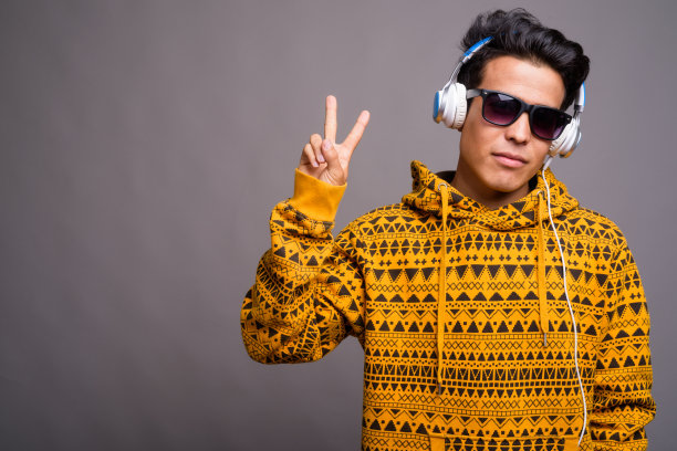 戴帽衫和太阳镜的亚洲青年听音乐的影棚照片图片下载