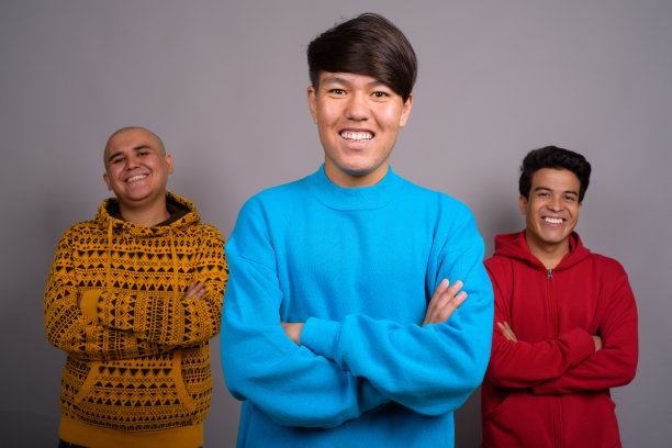 一群身穿保暖服装的亚洲年轻男士的影棚照片，灰色背景图片下载