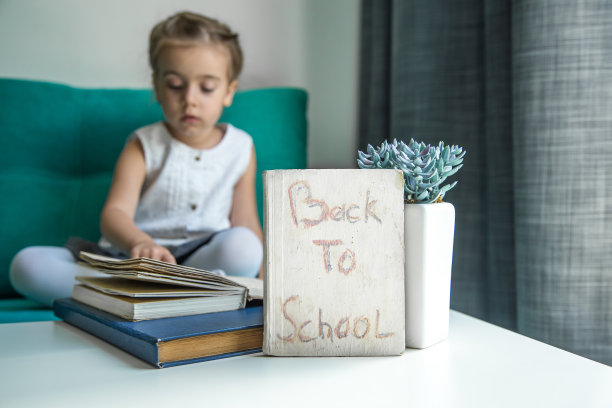 女孩坐着，手里拿着一本书回到学校图片下载