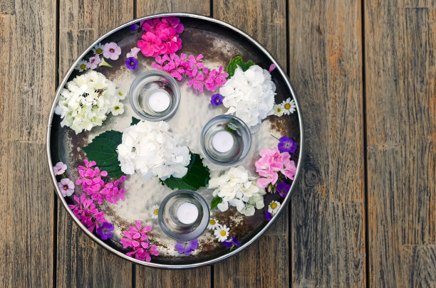一个扁平的金属圆碗，盛着水和各种花;粉色，白色和雏菊在左边的图片，俯视图图片下载