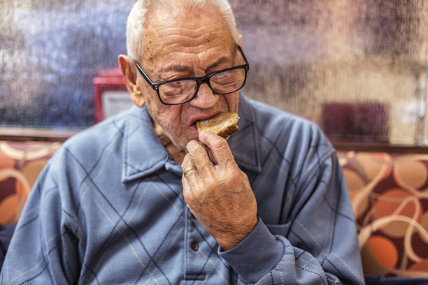 年长的成年男子早餐就餐者咬烤面包图片下载