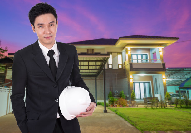 工程师手持头盔，背景为房屋图片下载