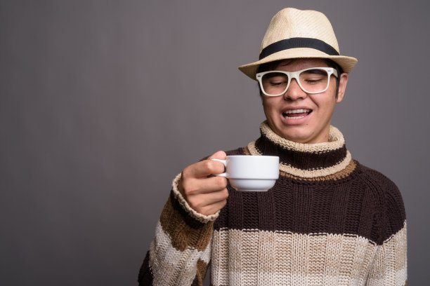 年轻亚洲少年的摄影棚照片，戴针织毛衣和帽子，灰色背景图片下载