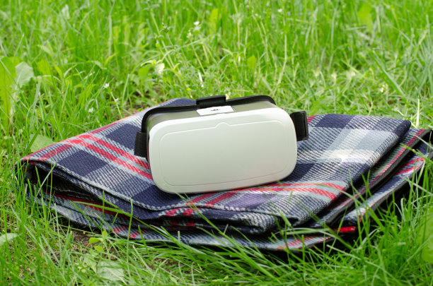带着虚拟现实头盔的格子图案躺在绿色的草地上图片下载