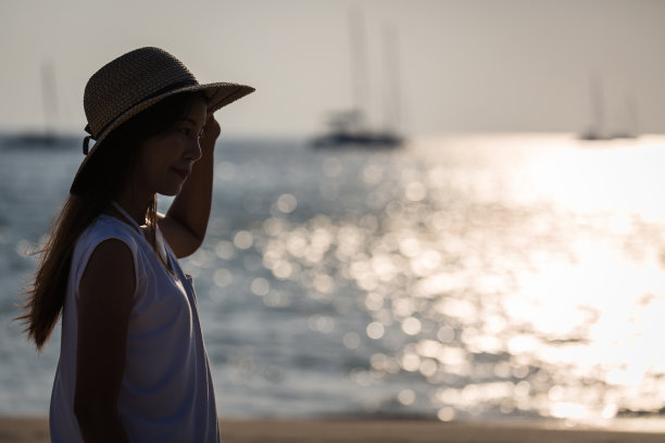 年轻的亚洲女人戴着帽子在海滩上图片下载