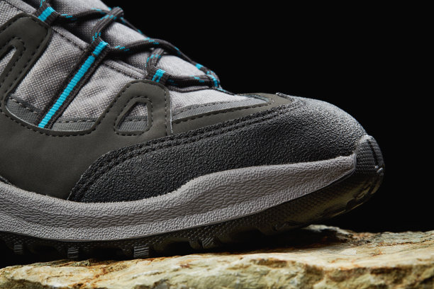 新的徒步靴上的岩石与黑色的背景图片下载