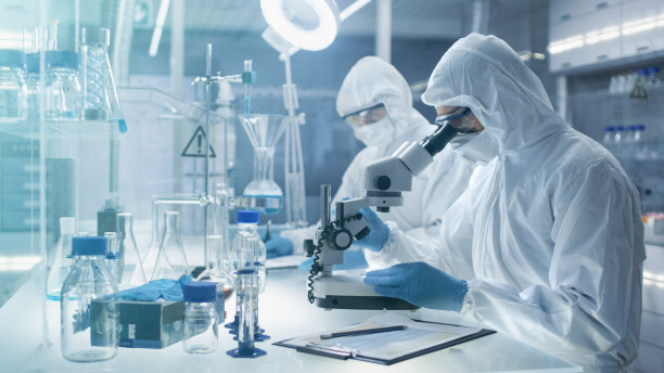 在一个安全的高水平实验室里，科学家们穿着工作服进行一项研究。化学家用钳子调整培养皿中的样品，然后在显微镜下检查它们，他的同事写下结果。图片下载