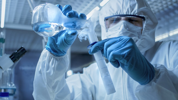 在一个安全的高水平研究实验室的科学家混合从试管吸烟化合物与物质在烧杯。图片下载