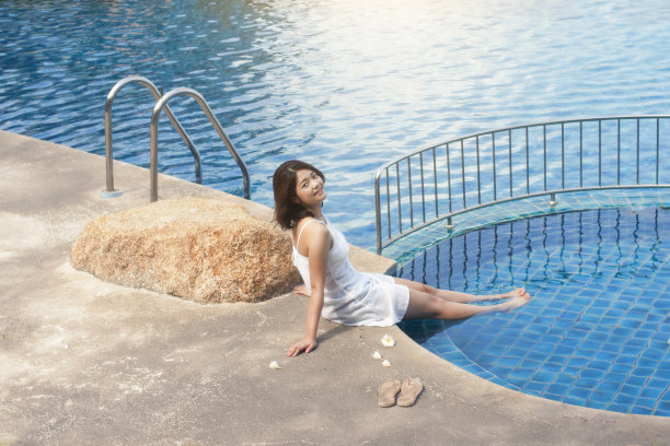 美丽的女人放松附近的游泳池。图片下载