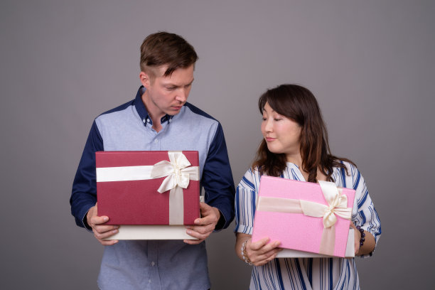 工作室拍摄的年轻英俊的商人和成熟的亚洲女商人在灰色的背景图片下载