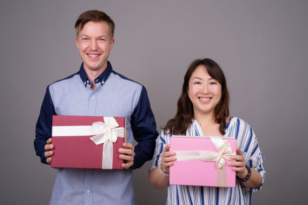 工作室拍摄的年轻英俊的商人和成熟的亚洲女商人在灰色的背景图片下载