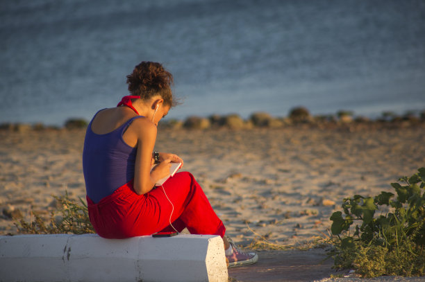 年轻的女孩写日记和听音乐的海滨夏季镇阿瓦里克图片下载