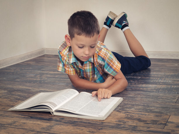 小孩子在看书。男孩躺在房间的地板上图片下载