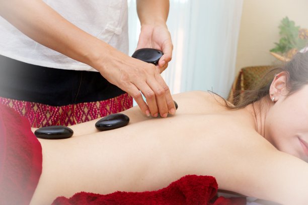 女人正在花时间在热石压迫的日间水疗皮肤治疗图片下载