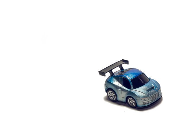 那辆运动的蓝色玩具车有一个白色背景上的黑色扰流板。图片下载