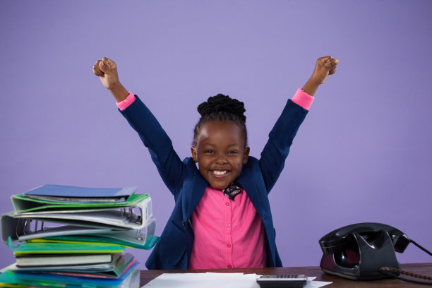 快乐的女商人在办公桌前举起手臂的肖像图片下载