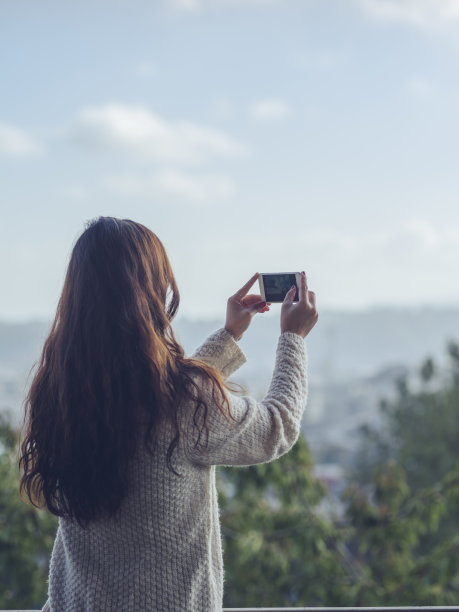 用智能手机拍照的女性后视图图片下载